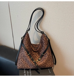 Detailed close-up of leopard print shoulder bag with black leather straps and gold hardware