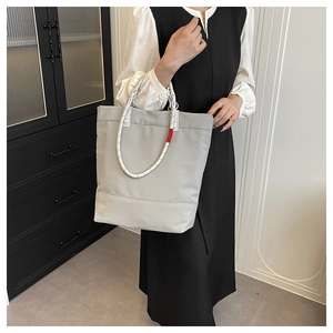 Gray tote bag with rope handles worn by model in minimalist indoor setting