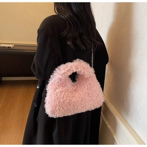 Rosa Plüschtasche mit silberner Kette, präsentiert auf einem schwarzen Mantel