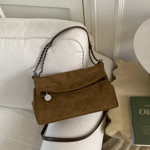 Detail of brown suede crossbody bag with quilted diamond pattern and silver chain