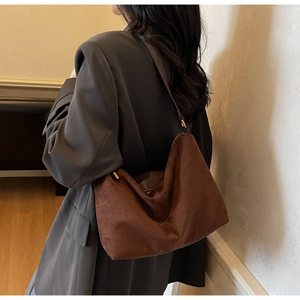 Detail of a brown suede hobo bag featuring fine texture and golden adjustable buckle strap