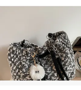 Detail of tweed tote bag with metal chain strap and white monster plush pendant