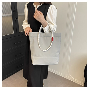 Detail of light grey tote bag featuring distinctive black and white braided rope handles