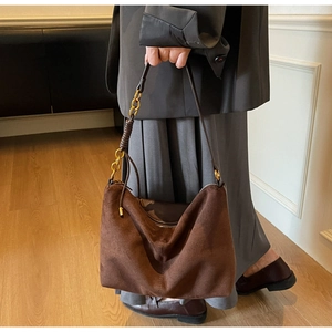 Detail of dark brown suede hobo bag featuring gold chain strap and soft texture