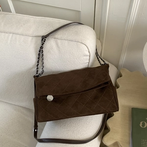 Detail of dark brown suede shoulder bag featuring quilted lattice pattern and silver chain