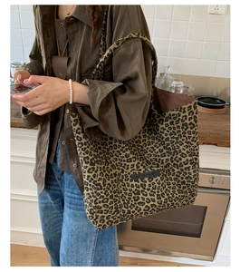Detailed view of leopard print tote bag with side pocket shown on shoulder in a room