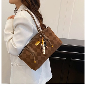 Close-up of brown quilted faux suede tote bag featuring a wooden beaded handle ornament