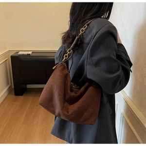 Detail of vintage brown suede tote bag with golden chain strap on a business suit