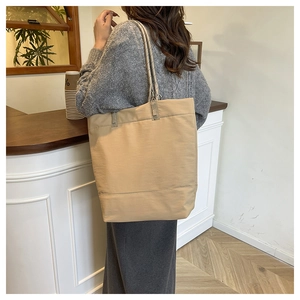 Large khaki tote bag with rope handles shown in a casual lifestyle cafe setting