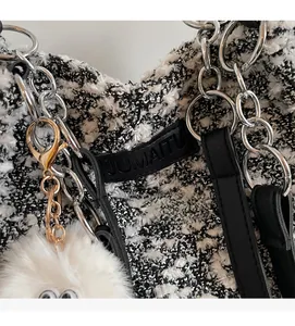 Detail of black and white tweed texture with silver chain and white plush monster charm