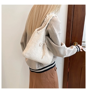 Detail of cream knit shoulder bag with bow, showing texture on model in soft light