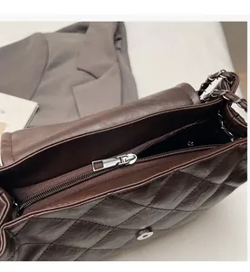 Détail de la fermeture éclair argentée et du fermoir magnétique sur le sac marron foncé