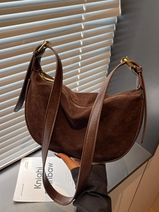Brown suede hobo shoulder bag with leather strap and golden hardware in natural light