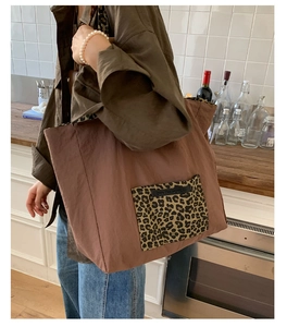 Side view of a large brown tote bag with leopard print pocket shown in a modern kitchen