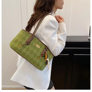 Detail of green knit tote bag with brown leather trim and bohemian wooden bead tassel