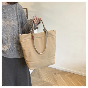 Detail of beige tote bag with unique dual-tone woven rope handles and red label tag