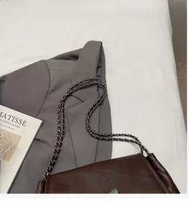 Détail d'un sac cabas marron matelassé avec bandoulière chaîne et blazer gris chic