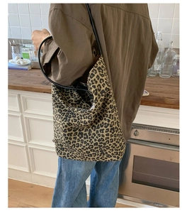 Detailed side view of leopard print tote bag with black straps in a cozy kitchen setting