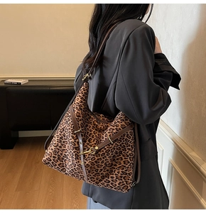 Detail of leopard print hobo bag with brown leather trim worn by model in a stylish interior