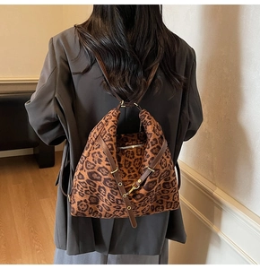 Detail showing the leopard print pattern and brown leather strap on a large bucket bag