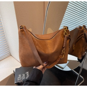 Detail view of caramel suede shoulder bag with gold chain and side woven leather accents