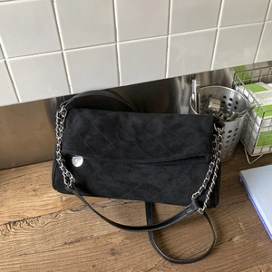 Detail of black suede crossbody bag featuring quilted patterns and silver chain strap