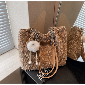 Detailed view of brown plush tote bag with gold chain strap and fluffy charm