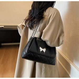 Vue portée d'un sac cabas en cuir noir matelassé avec boucle papillon argentée