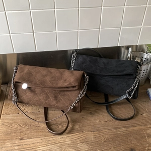 Detail of coffee and black suede crossbody bags with quilted pattern and chain straps