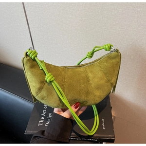 Detail of avocado green suede crescent bag with fringe accents and knotted shoulder strap