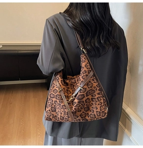 Close-up of leopard print tote bag with brown leather straps and gold metal eyelets