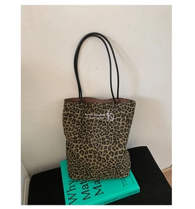 Detailed close-up of leopard print tote bag with embroidery on blue book backdrop