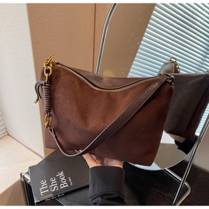 Macro detail of vintage brown suede and smooth leather bag with gold metal chain accent