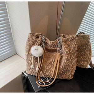 Close-up of brown faux shearling tote bag with leather logo tag and plush charm