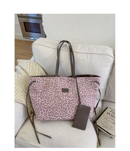 Détail d'un sac cabas à imprimé léopard rose avec des lanières en cuir sur un canapé