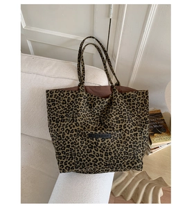 Close-up of leopard print tote bag with double handles and OWN THE MOMENT label on fabric