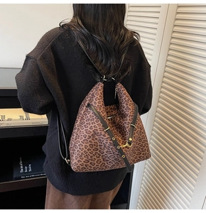 Detailed view of leopard print shoulder bag with black strap and golden buckle