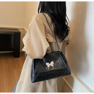 Détail du sac fourre-tout matelassé noir avec boucle papillon argentée et bandoulière
