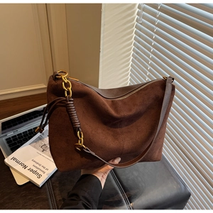 Detail view of brown suede hobo bag featuring vintage gold chain and long shoulder strap