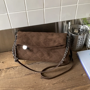 Detail of dark brown suede shoulder bag featuring diamond quilted pattern and chain strap