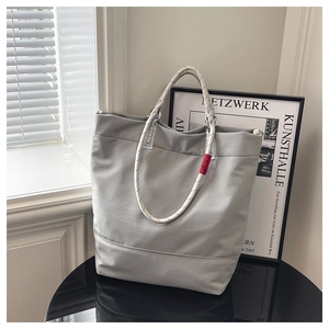 Detail of grey tote bag featuring thick black and white textured rope handles