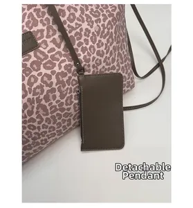 Détail du sac cabas léopard avec un pendentif amovible en cuir et une fermeture éclair