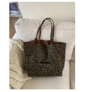 Detail of leopard print canvas tote bag featuring front pocket on a cozy cream sofa