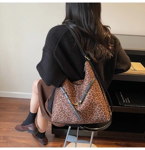 Detail of leopard print bucket bag with black leather strap and golden metal buckle