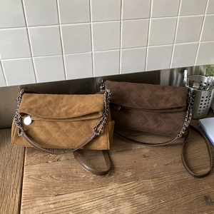 Close-up of suede quilted crossbody bags in brown and camel on a rustic wooden table