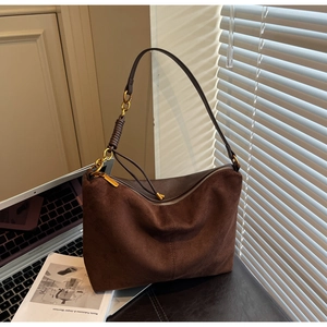 Detail of vintage brown suede tote featuring gold chain strap and textured shadow effect