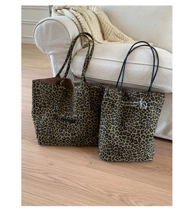 Detail of leopard print tote bags featuring embroidered puppy and white text on canvas