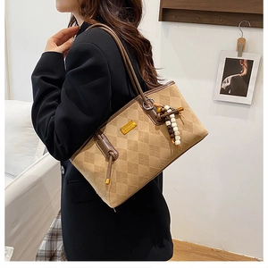 Retro brown quilted shoulder bag with beaded tassel worn by a model in a black blazer