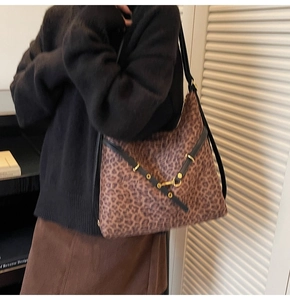 Close-up of leopard print tote bag with black leather straps and gold metal buckles