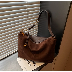 Detailed view of brown suede tote bag with vintage gold ring and leather wrap ornament